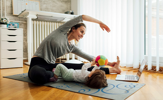 Breastfeeding mom practices yoga with baby nearby to relieve stress