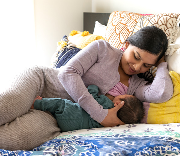 The mother lying on her side facing the baby in a tummy to tummy position.